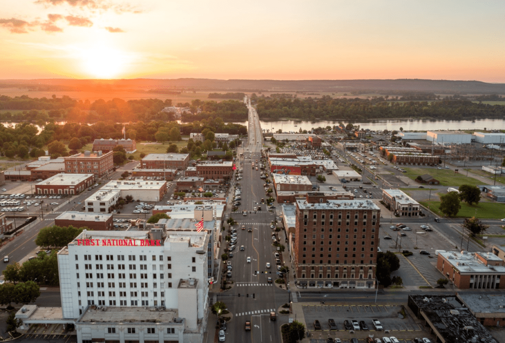 Municipal skyline at sunset overlooking a small downtown and river, representing how MSPs help local governments prevent ransomware attacks and service disruptions.