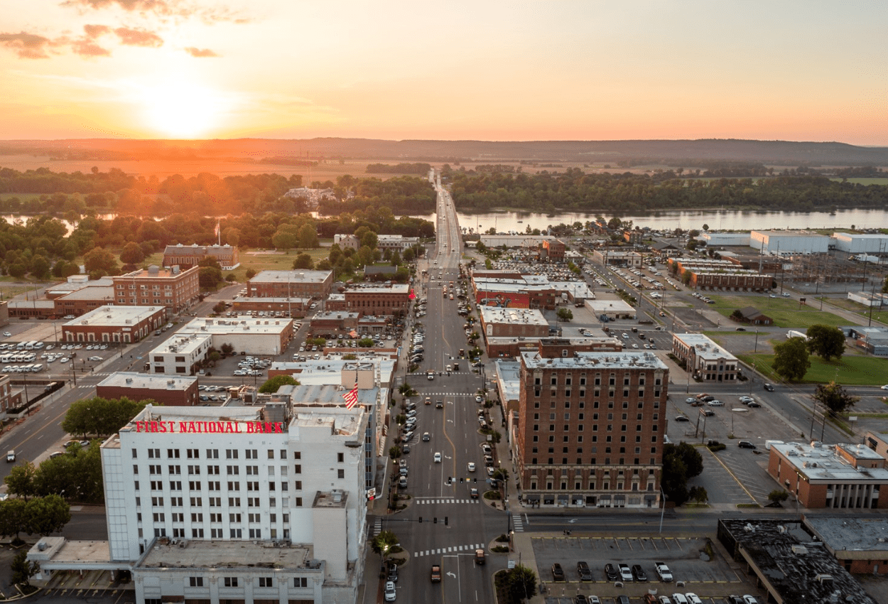 Municipal skyline at sunset overlooking a small downtown and river, representing how MSPs help local governments prevent ransomware attacks and service disruptions.