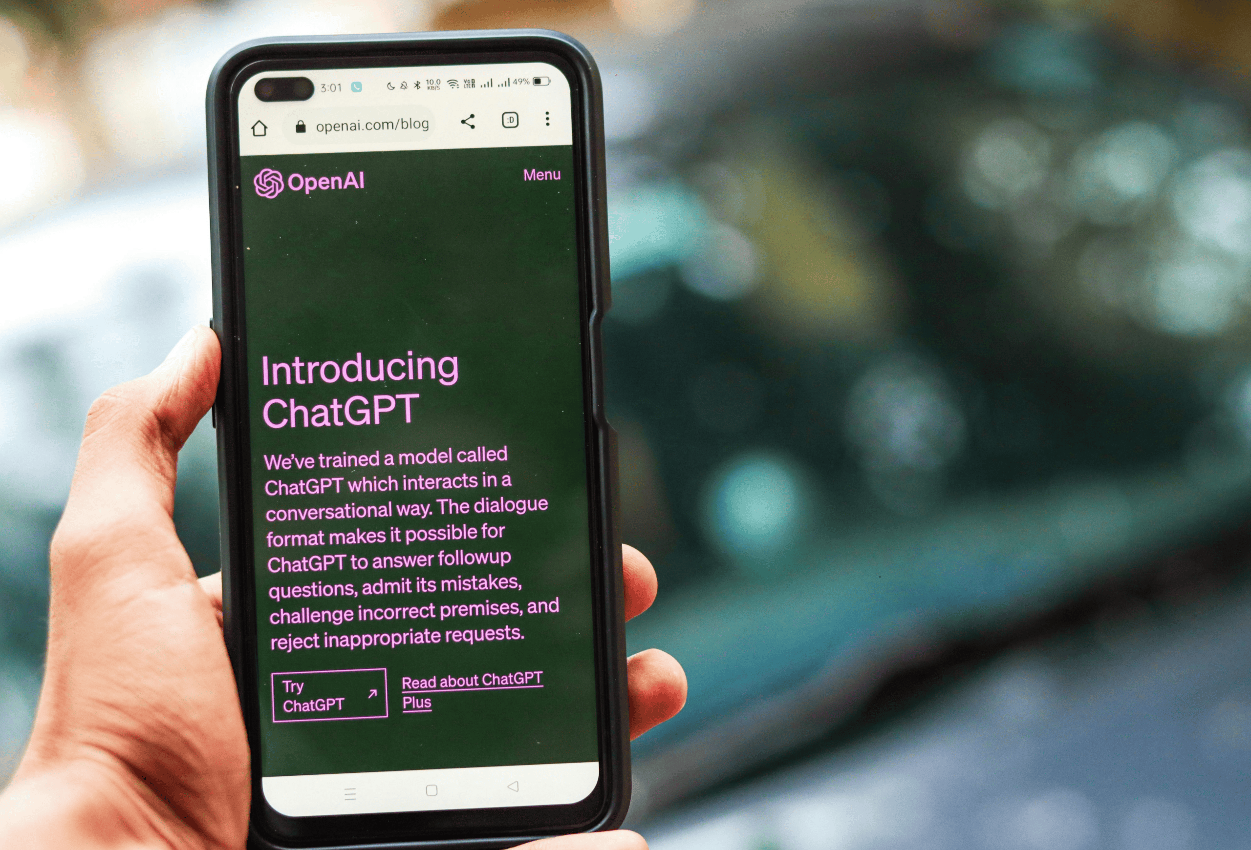 Person holding a smartphone displaying the OpenAI ChatGPT website.